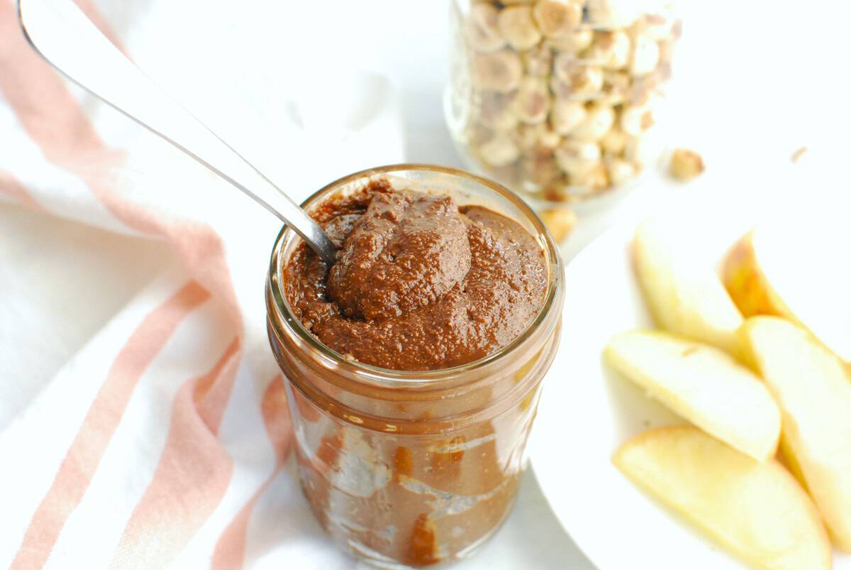 A spoon stuck into a jar of chocolate hazelnut butter.