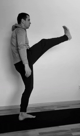 A man doing high kicks as part of a running warm up.