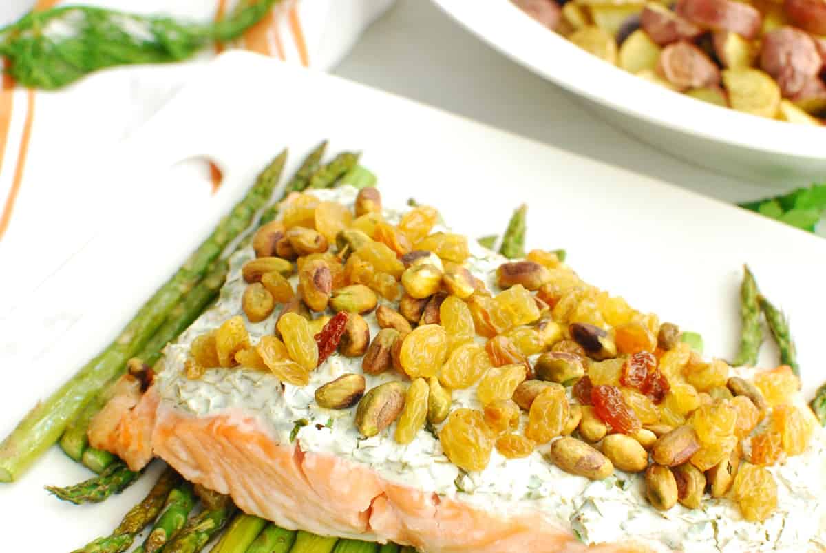 Close up view of the raisins and pistachios on top of a piece of salmon.