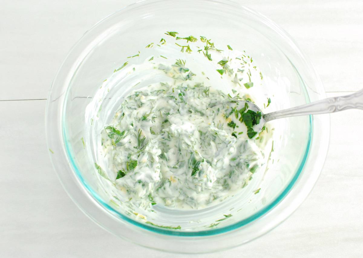 A small glass mixing bowl with the herb yogurt sauce.