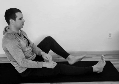 A male runner doing a seated hamstring stretch.