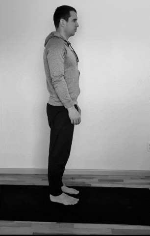 A man doing a standing hamstring stretch.