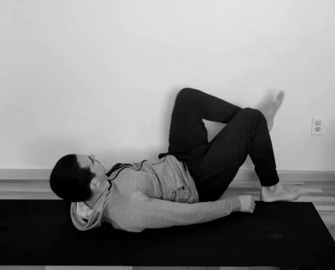 A male runner doing a wall hamstring stretch.