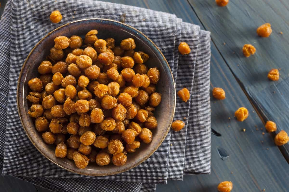 A wooden bowl full of roasted chickpeas.