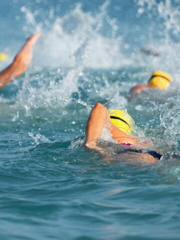 Triathletes with yellow swim caps during the swim portion of a race.