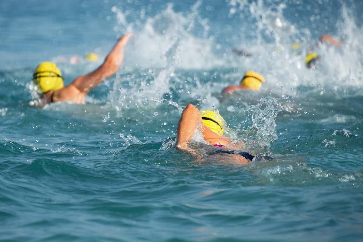 Triathletes with yellow swim caps during the swim portion of a race.