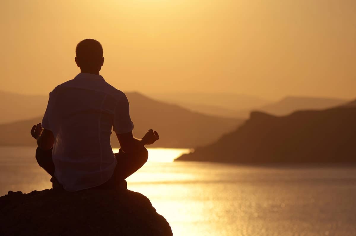 A triathlete meditating at sunset.