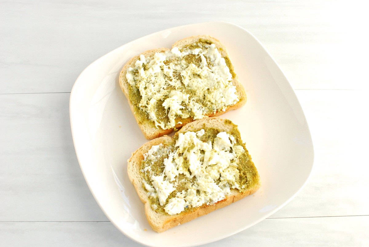 Two slices of toast with pesto and burrata on top.