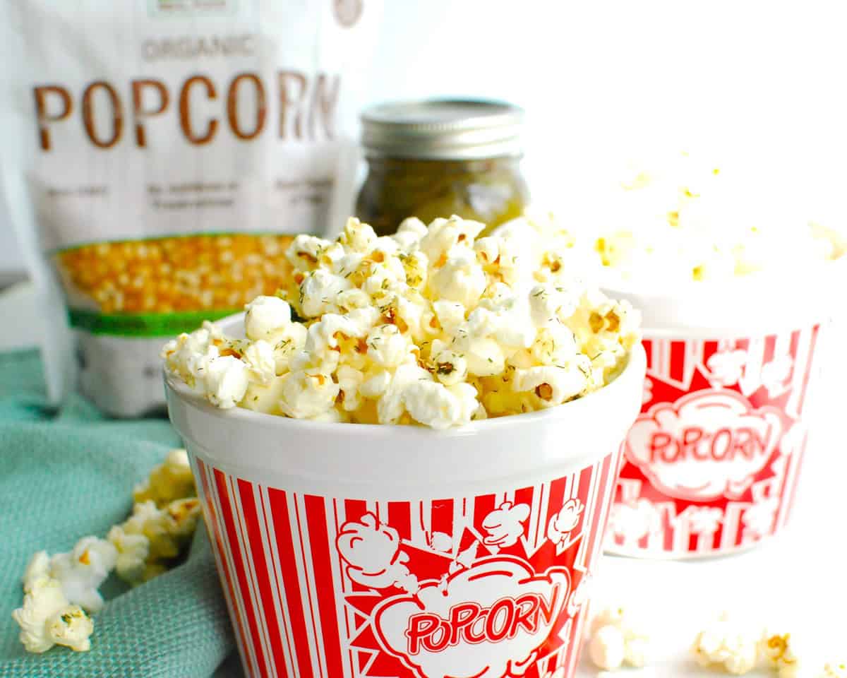 A popcorn bowl full of dill pickle popcorn, next to a napkin and another bowl.
