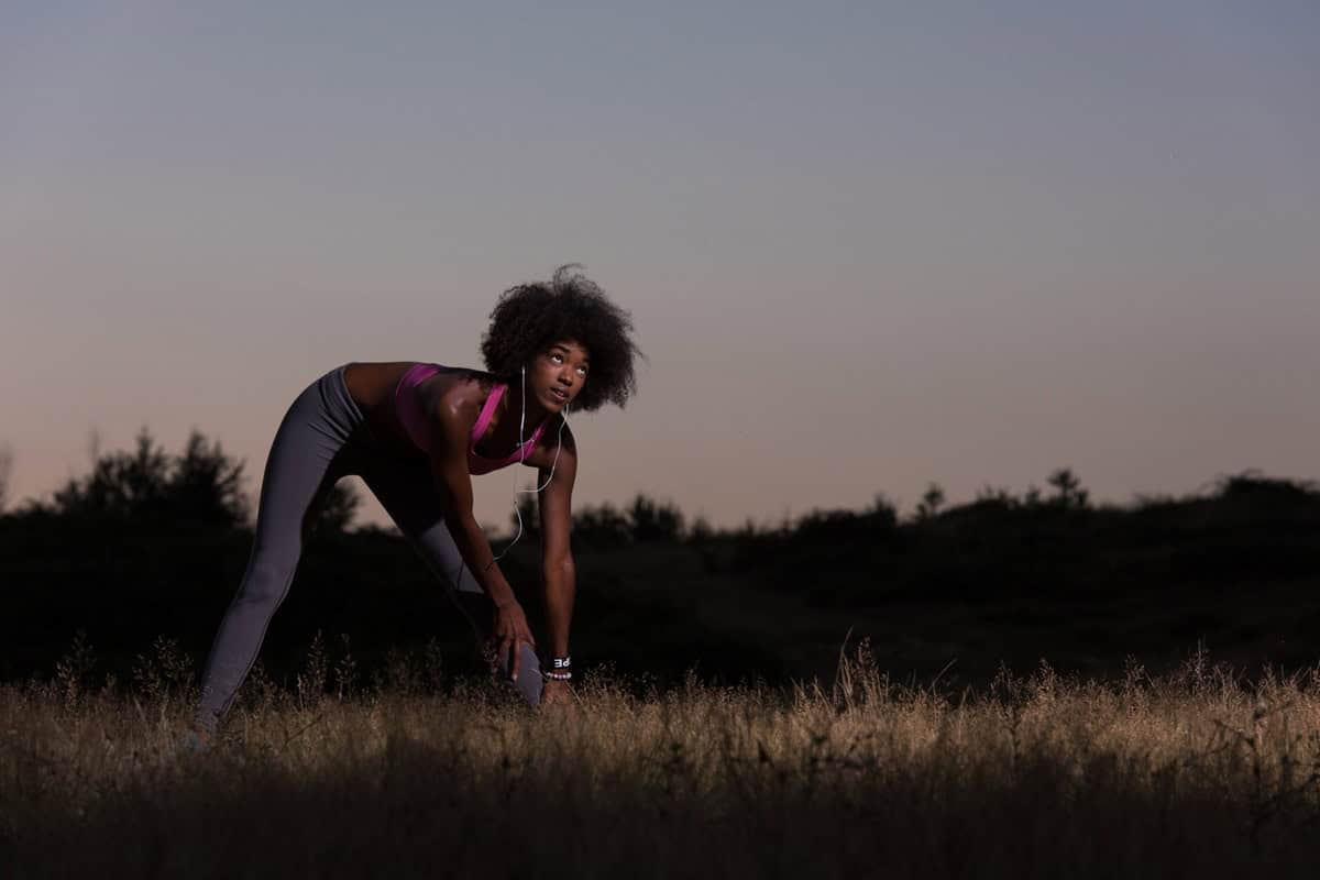 A runner doing stretches in the early evening outside after a run.
