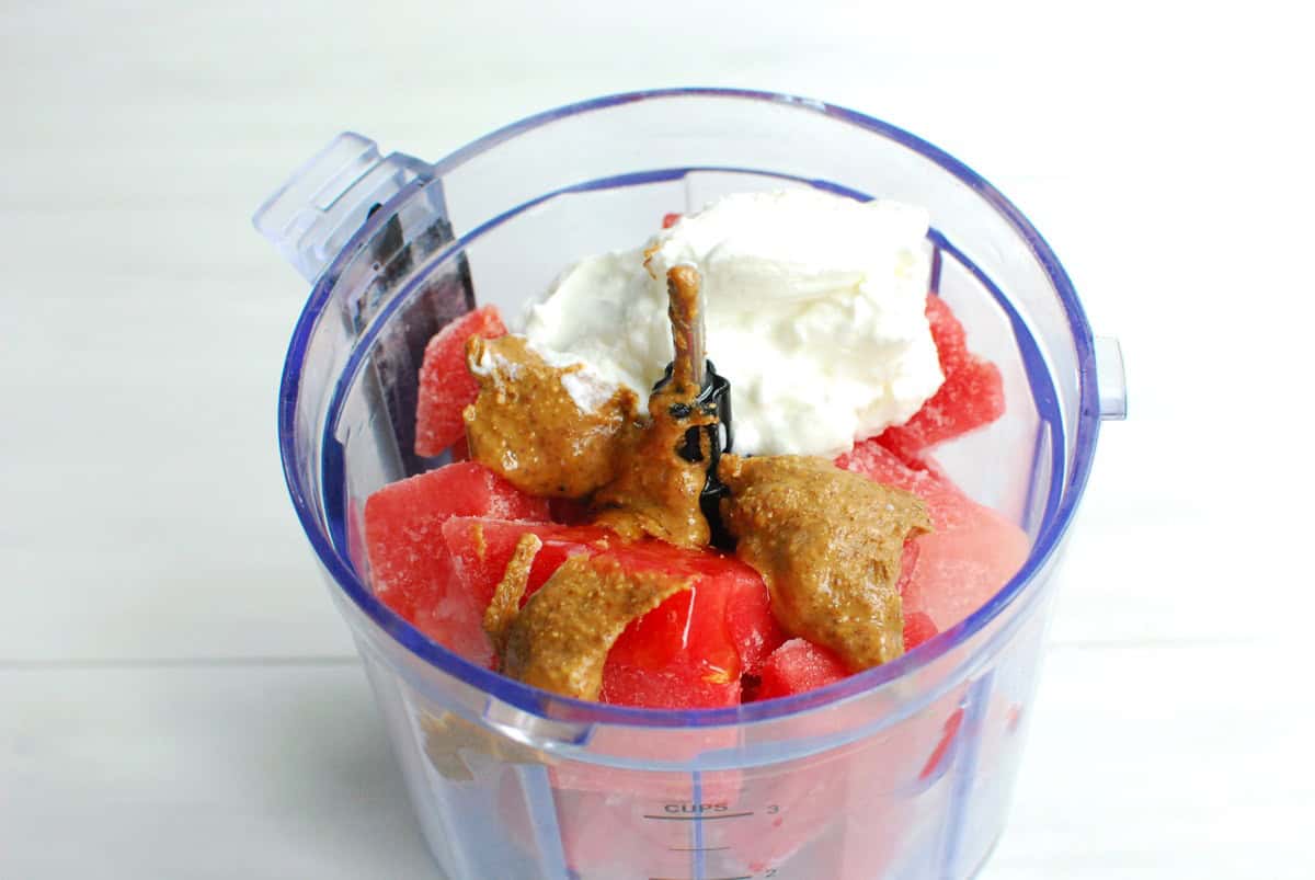 Watermelon, almond butter, yogurt, and honey added to a small food processor bowl.
