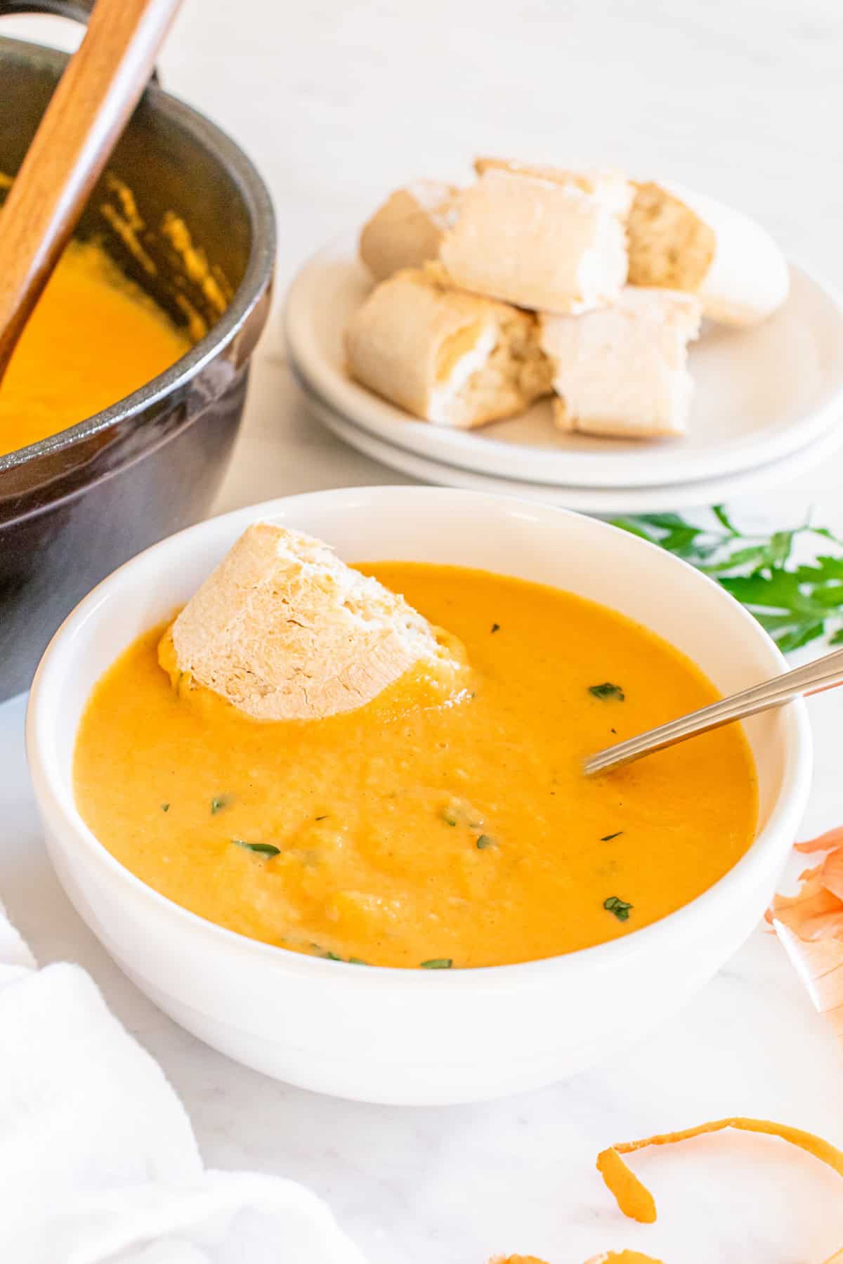 A piece of crusty bread dipped into a bowl of soup.