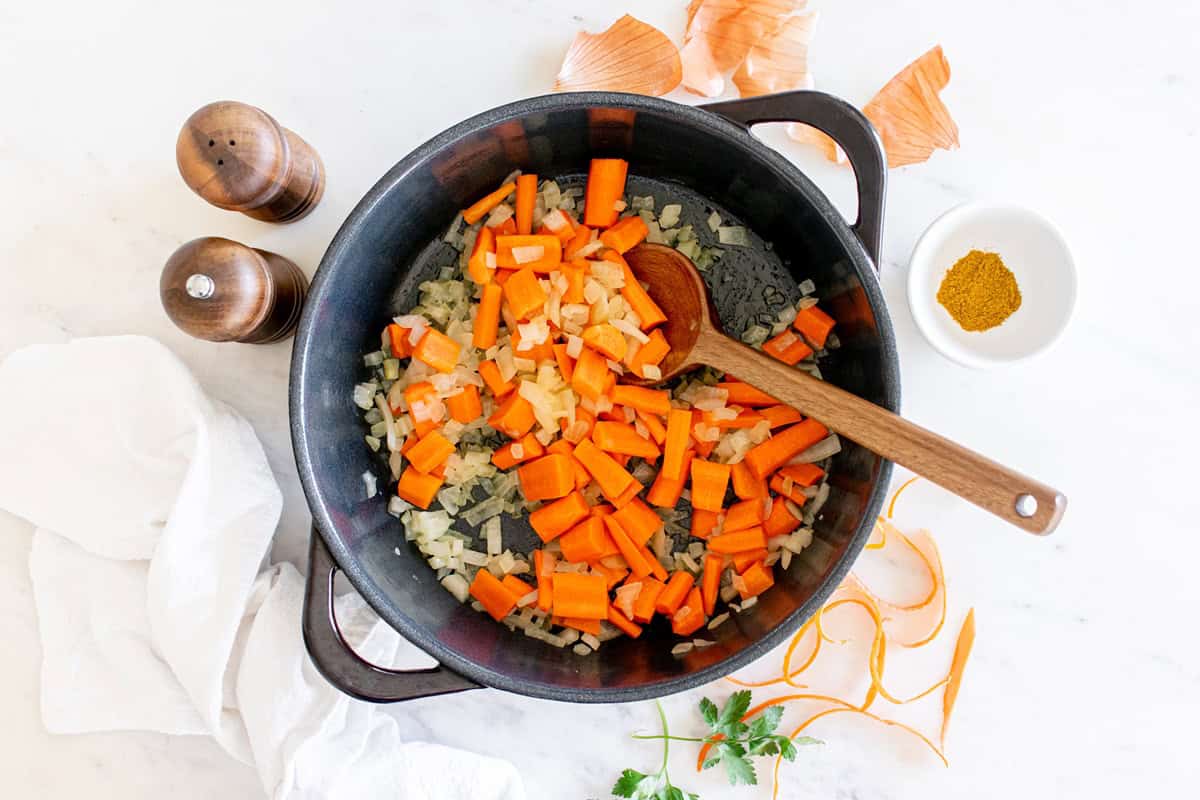 Onions and carrots sauteed in a pot.