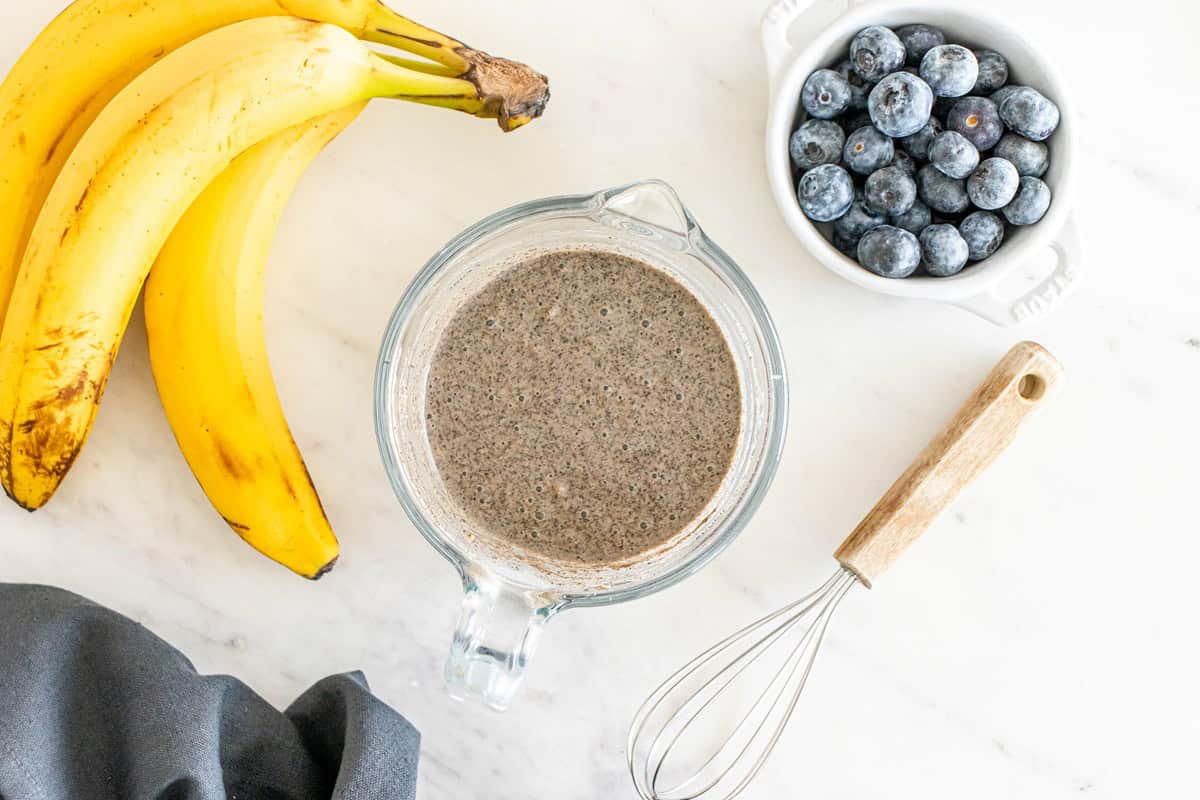 Dark colored pancake batter in a glass mixing bowl.