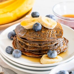 A big stack of high fiber pancakes topped with fruit and syrup.