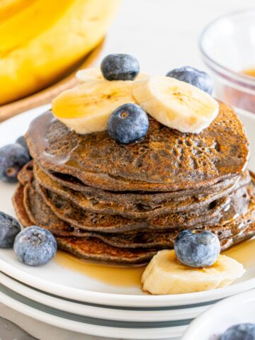 A big stack of high fiber pancakes topped with fruit and syrup.