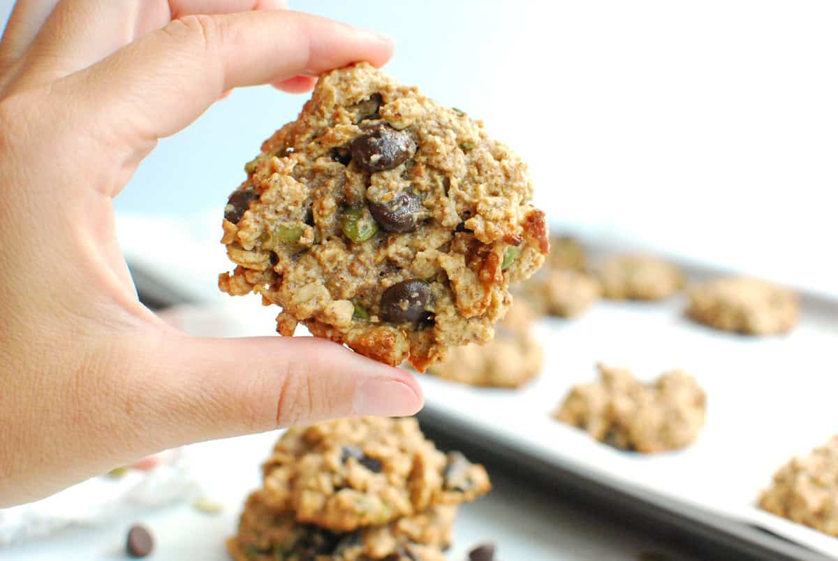 A woman's hand holding a trail mix breakfast cookie.