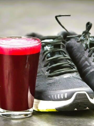 Beet juice next to a pair of running sneakers.