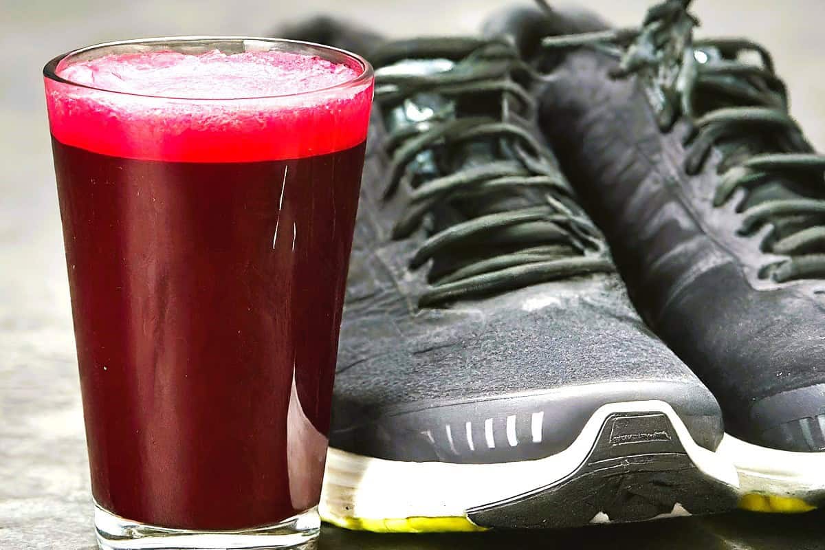 Beet juice next to a pair of running sneakers.