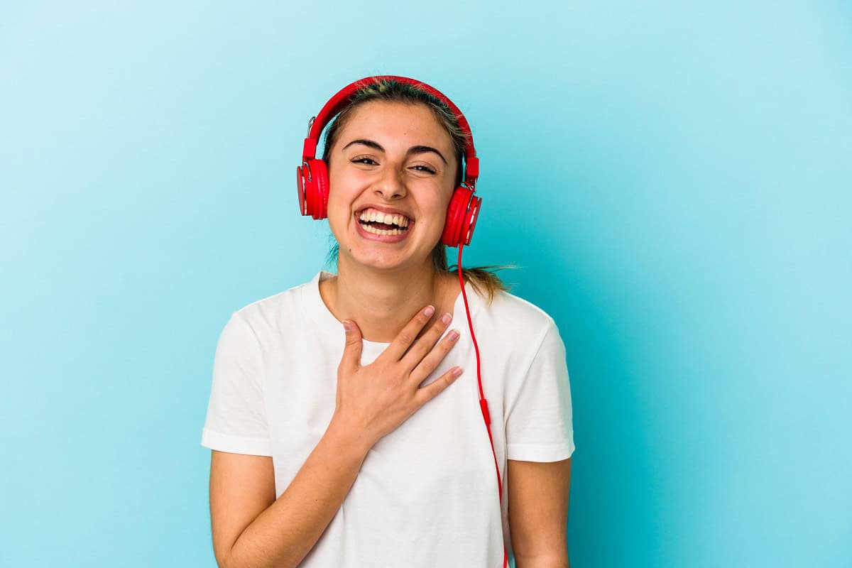 A young woman wearing headphones and laughing.