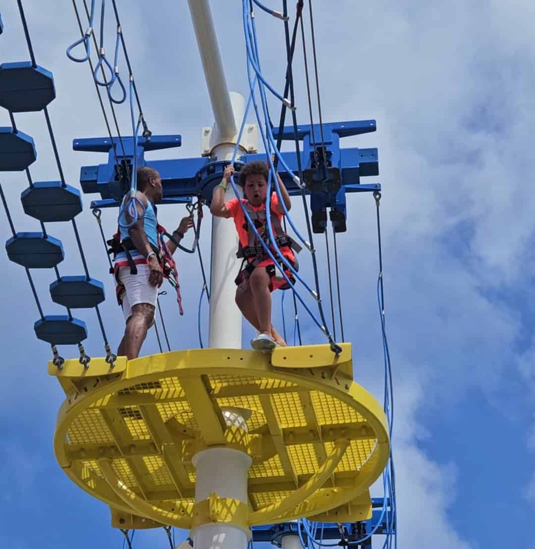 A father and son doing the ropes course on a cruise.