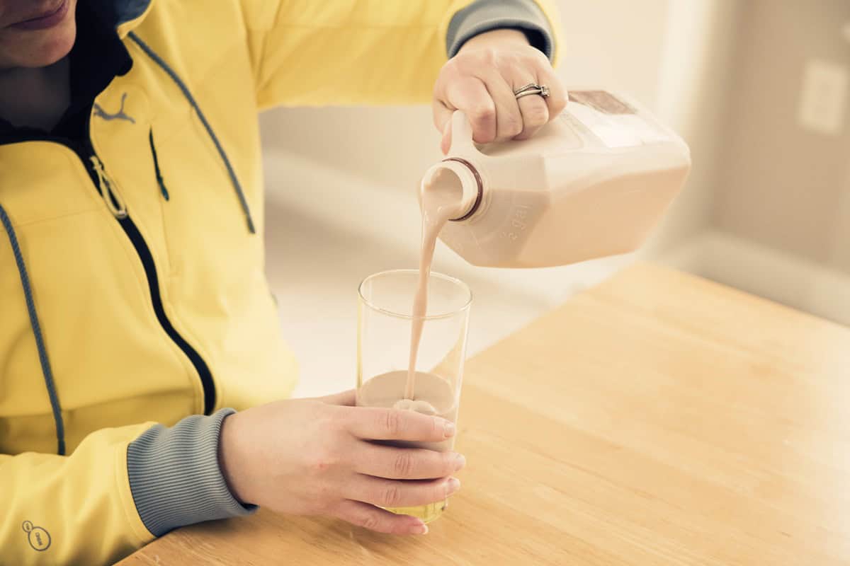 A person pouring a glass of chocolate milk.