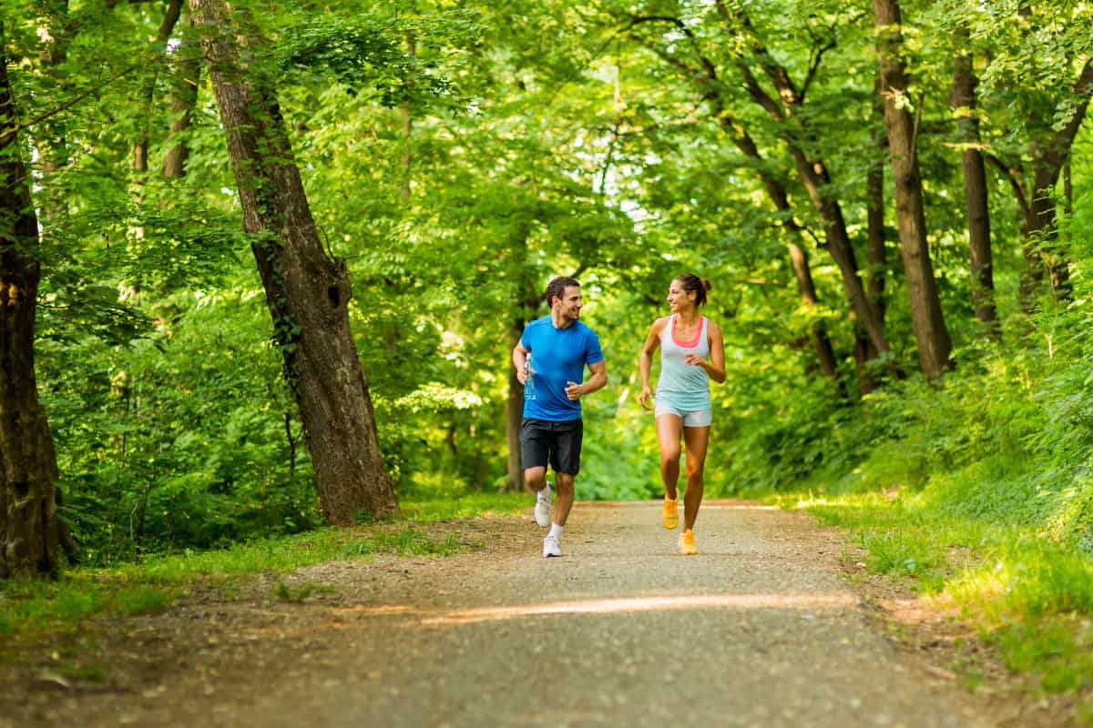 A male and female runner on a path in a park.
