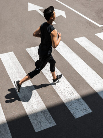 A runner going across a cross walk on a road.