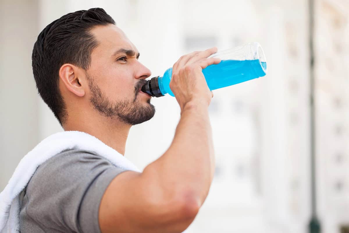 A man drinking a sports drink after his run.