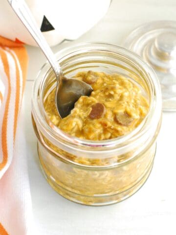 A jar filled with pumpkin protein overnight oats topped with a few chocolate chips.