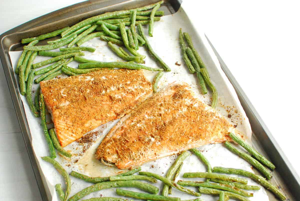 Cooked salmon and green beans on a baking sheet.