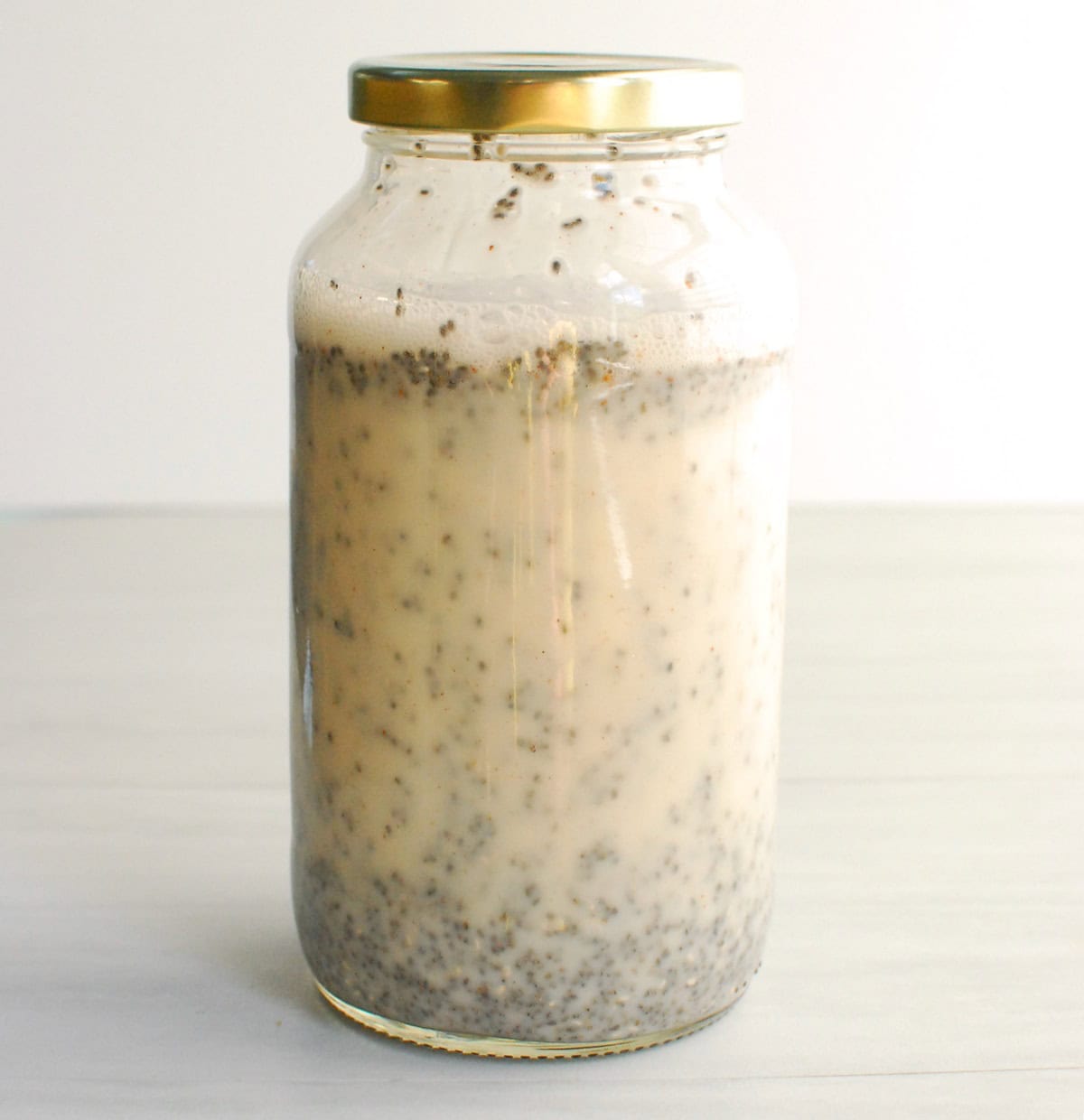 A large jar filled with chia seeds, almond milk, cinnamon, and maple syrup.