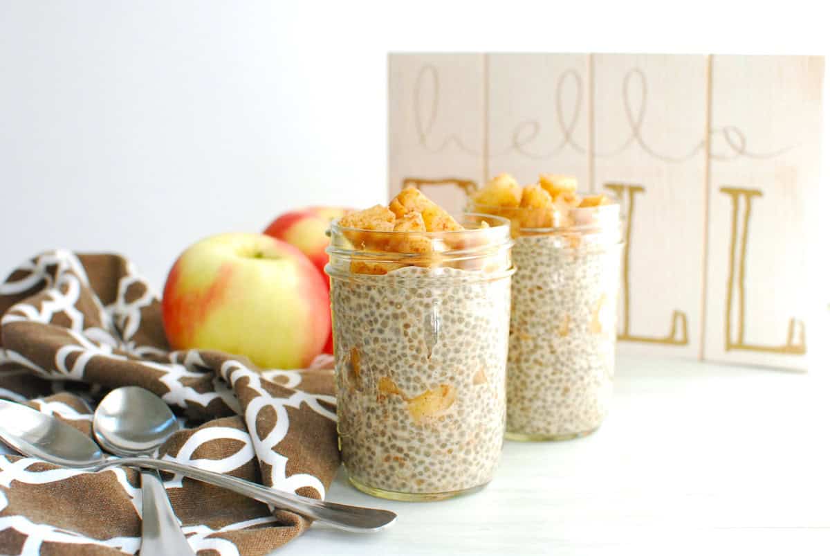 Two jars of apple chia pudding with spoons and a napkin next to them.