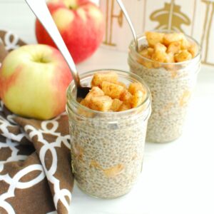 A small mason jar filled with apple pie chia pudding, with a spoon in the jar.