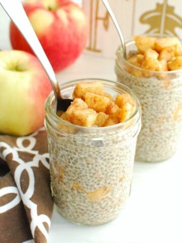 A small mason jar filled with apple pie chia pudding, with a spoon in the jar.