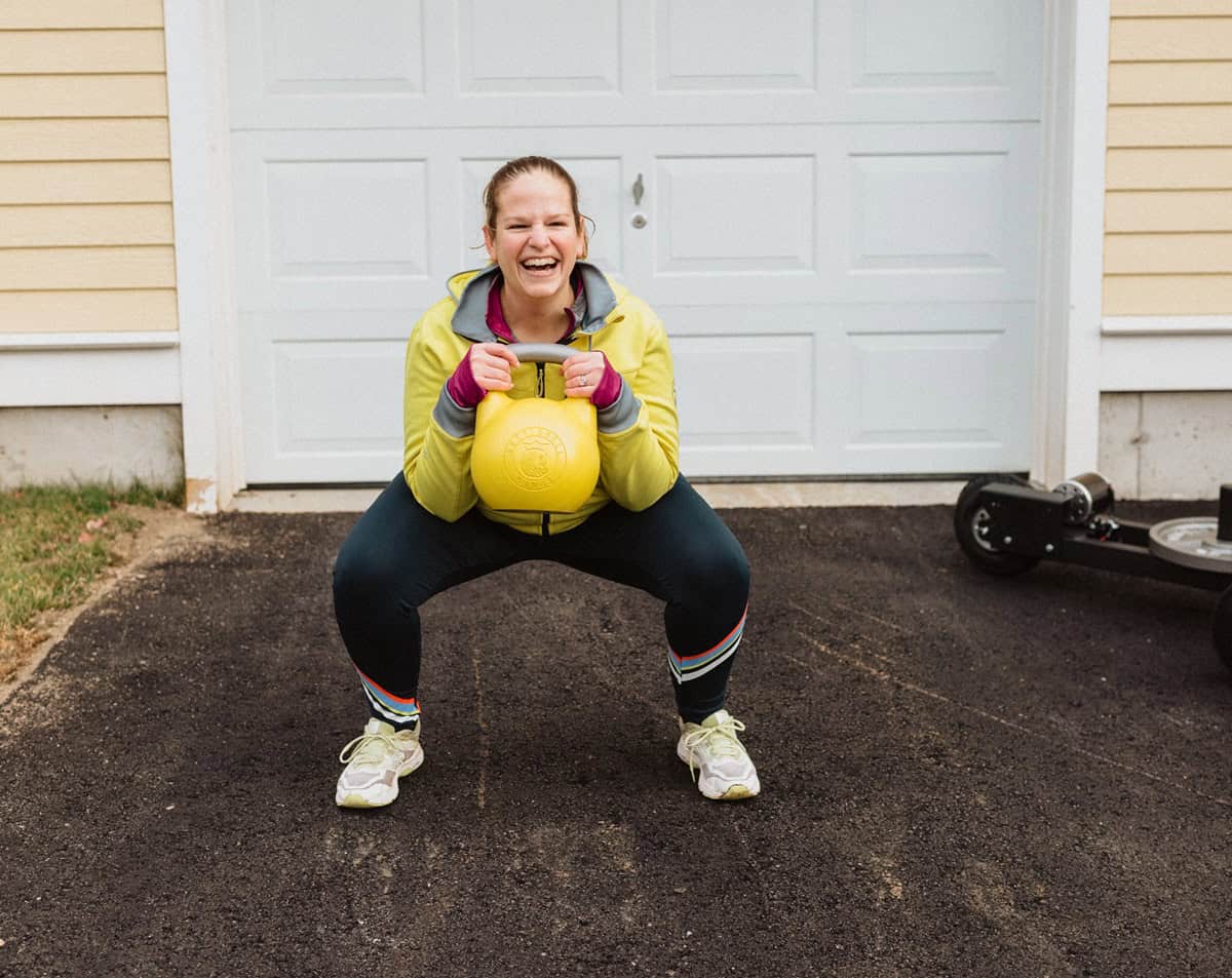 A woman doing a squat holding a kettlebell.