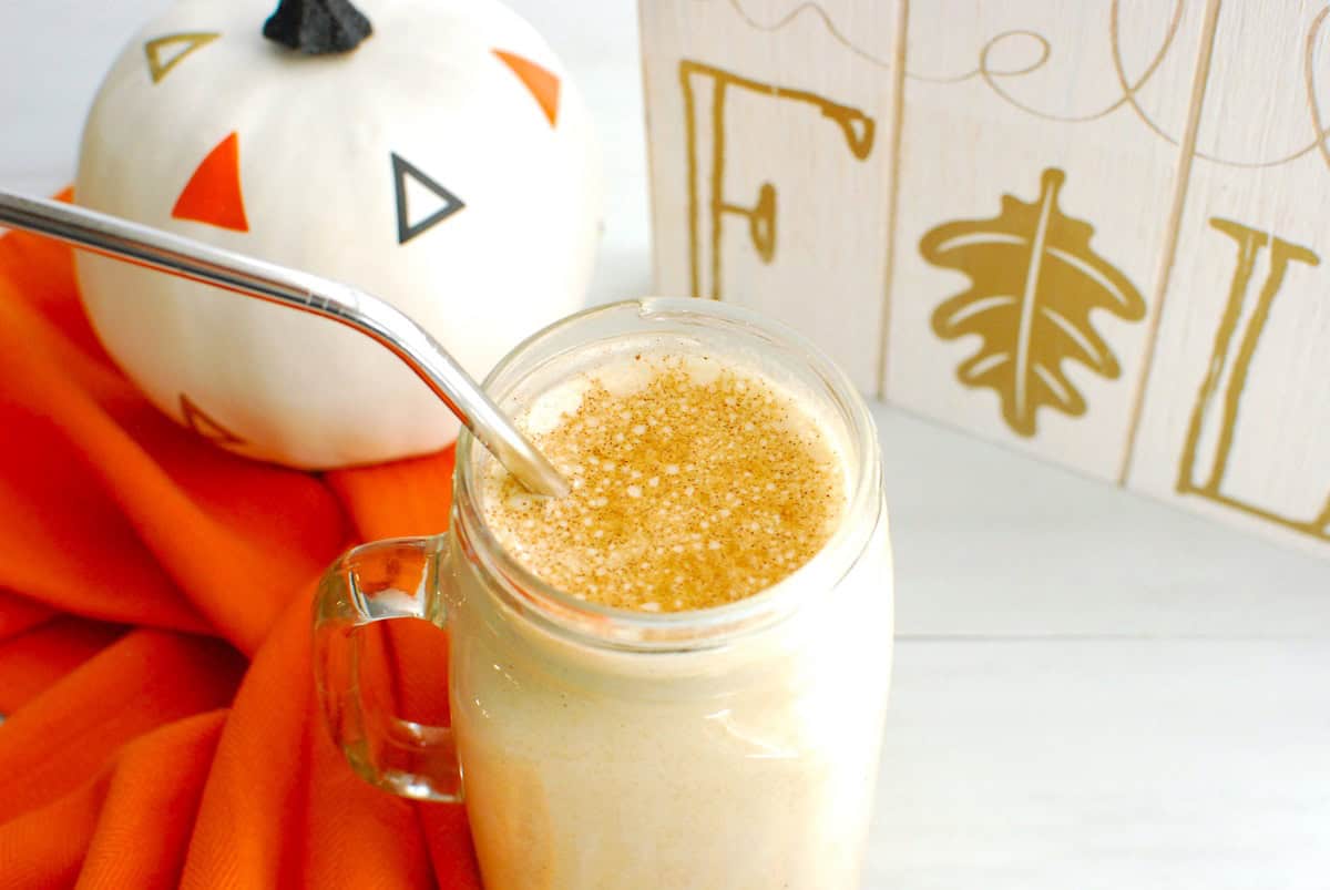 A high protein iced pumpkin spice latte in a mason jar with a metal straw.