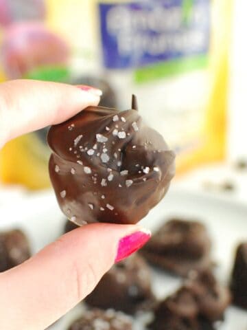 A woman's hand holding a chocolate covered prune.