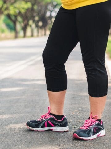 A woman's legs in running sneakers on a path, about to start running.