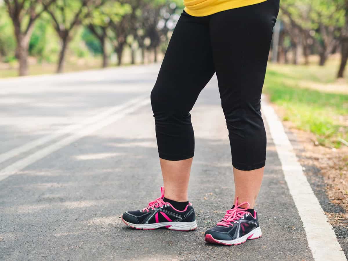 A woman's legs in running sneakers on a path, about to start running.