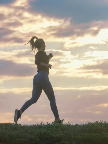 A female runner on a grass path.