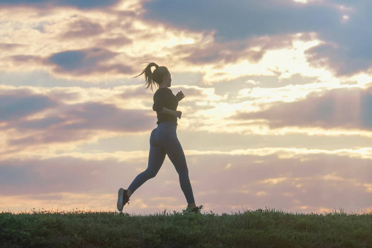 A female runner on a grass path.