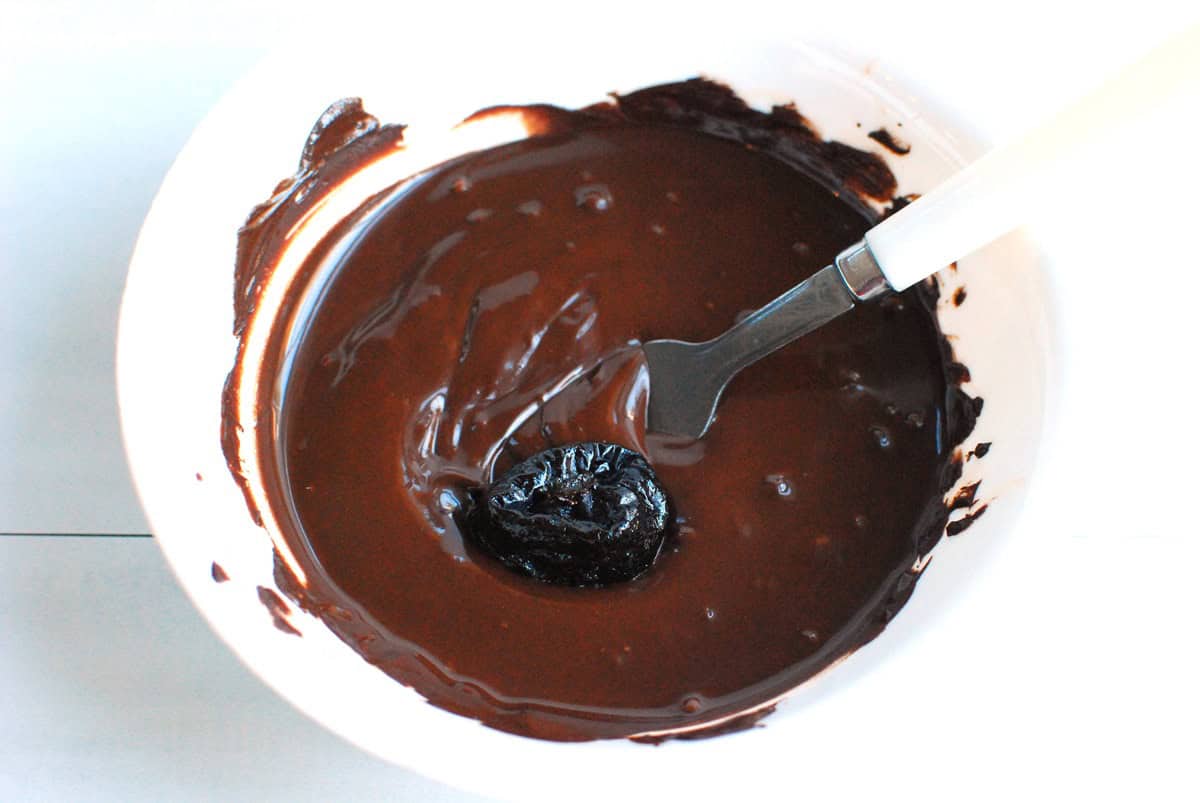 Dipping prunes into the melted chocolate.