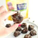 A woman's hand holding a chocolate covered prune.