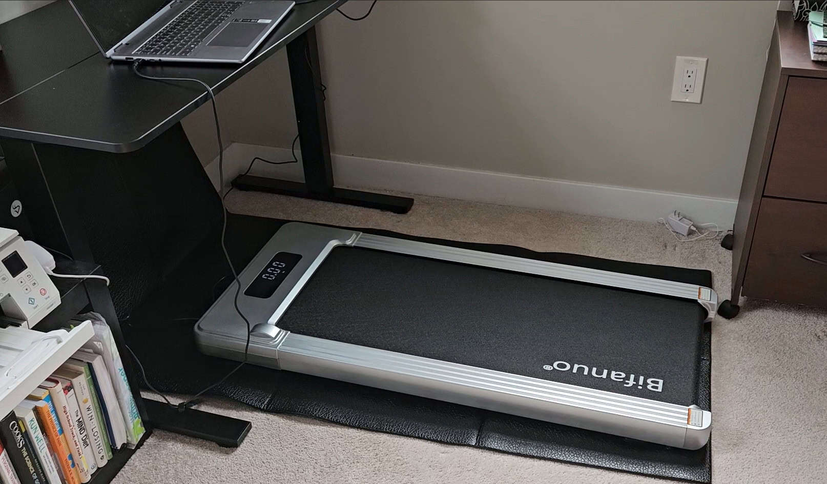 A walking pad on a mat in a home office.