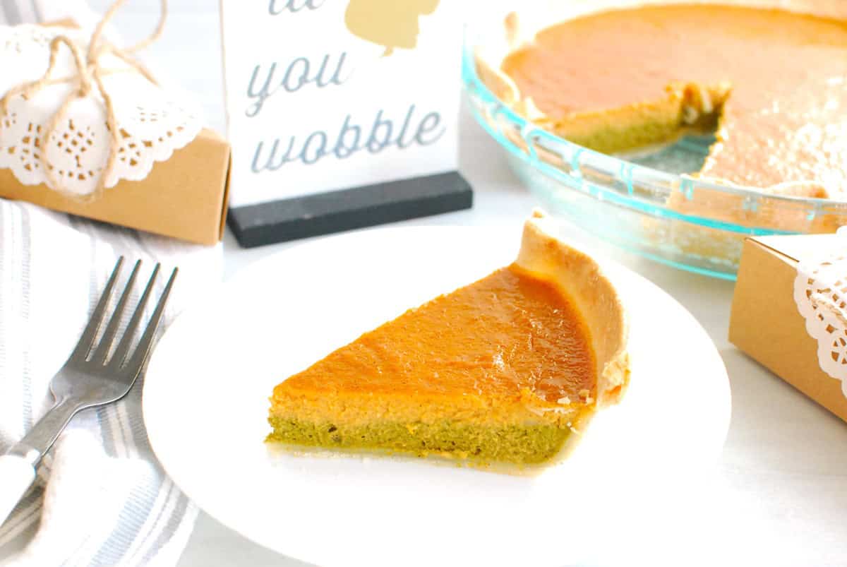 A slice of matcha pumpkin pie on a plate next to a fork and napkin.