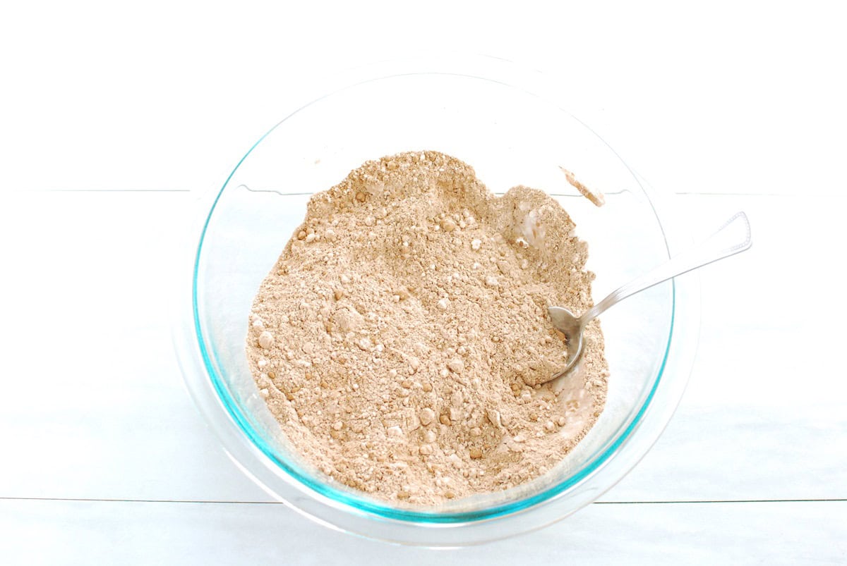 Flour, protein powder, cocoa powder, baking soda, and salt mixed together in a bowl.