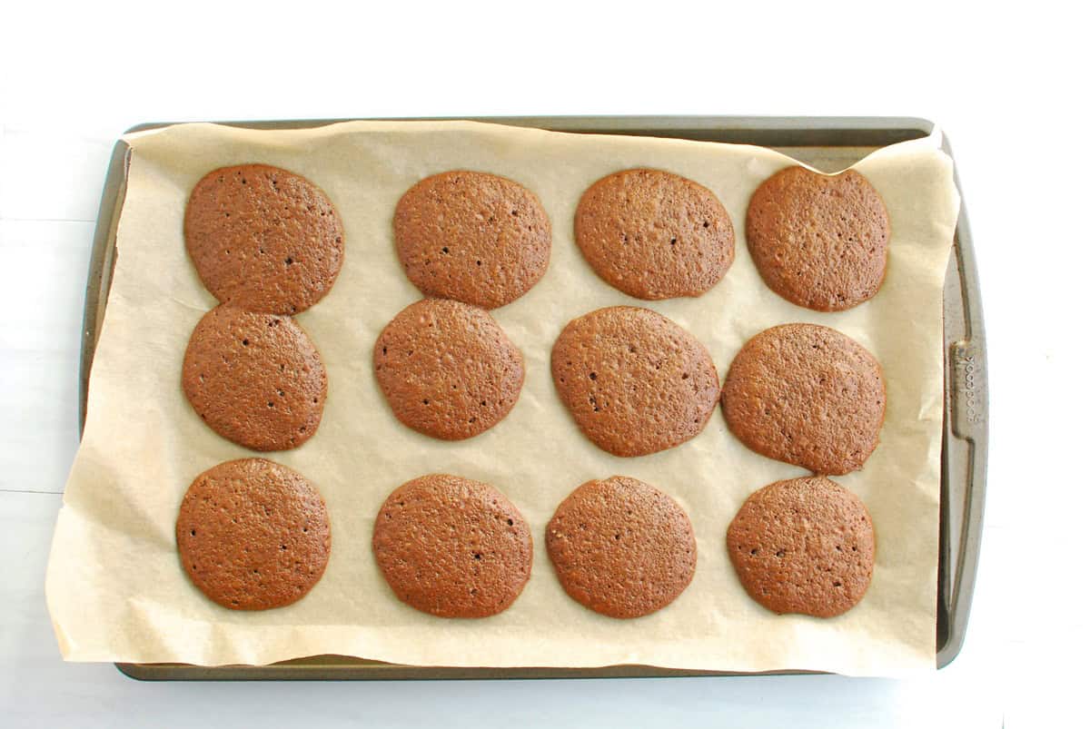 Just baked whoopie pie cakes on a parchment-lined baking sheet.