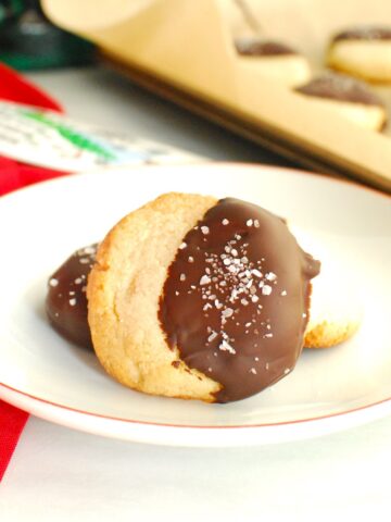 A close up of an almond flour shortbread cookie that was dipped in chocolate and sprinkled with coarse salt.