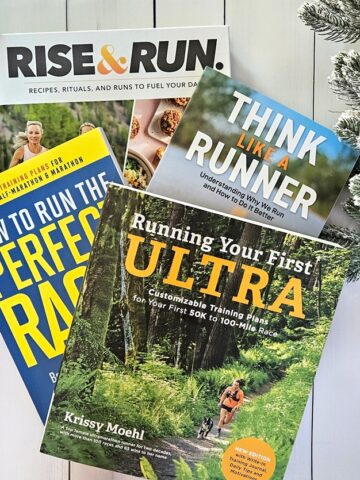 A bunch of running books next to Christmas decorations.